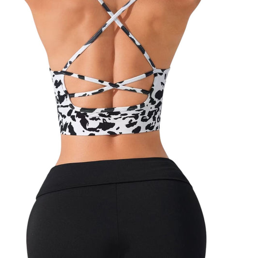 Simplix black and white cow print sports bra with thin crisscross straps, ideal for summer workouts.
